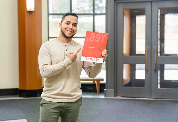 An image of student holding acceptance packet.